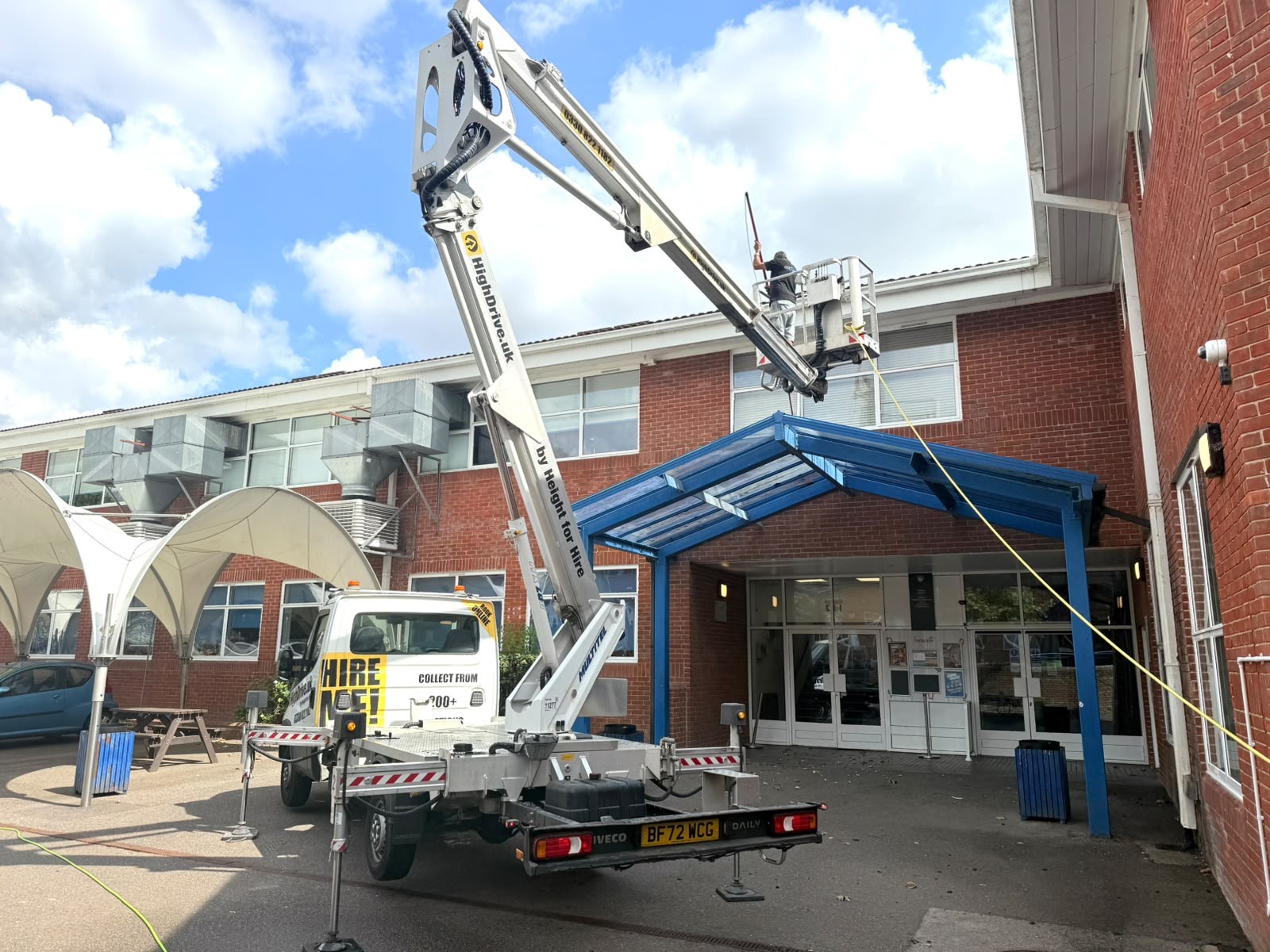 A PPC window cleaner using a water-fed pole from a cherry picker to clean windows on a commercial building in Sussex